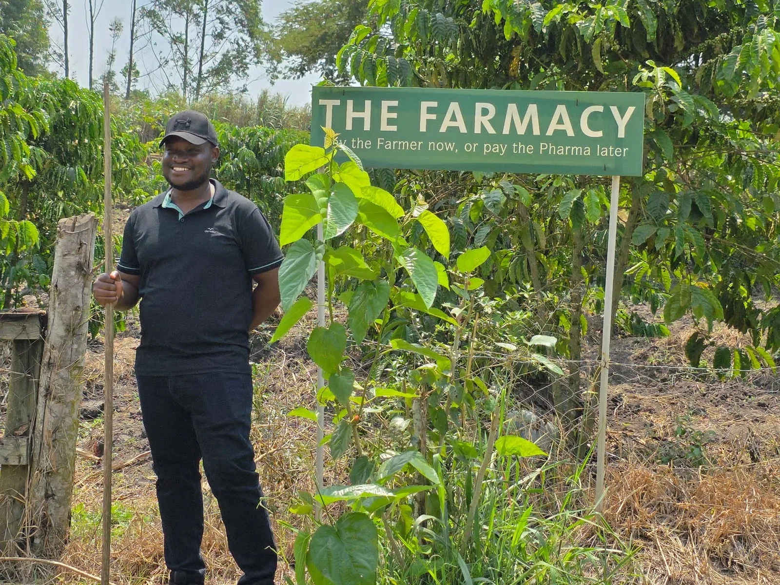 A guide beside 'The Farmacy' sign among the coffee bushes at our rustic farm