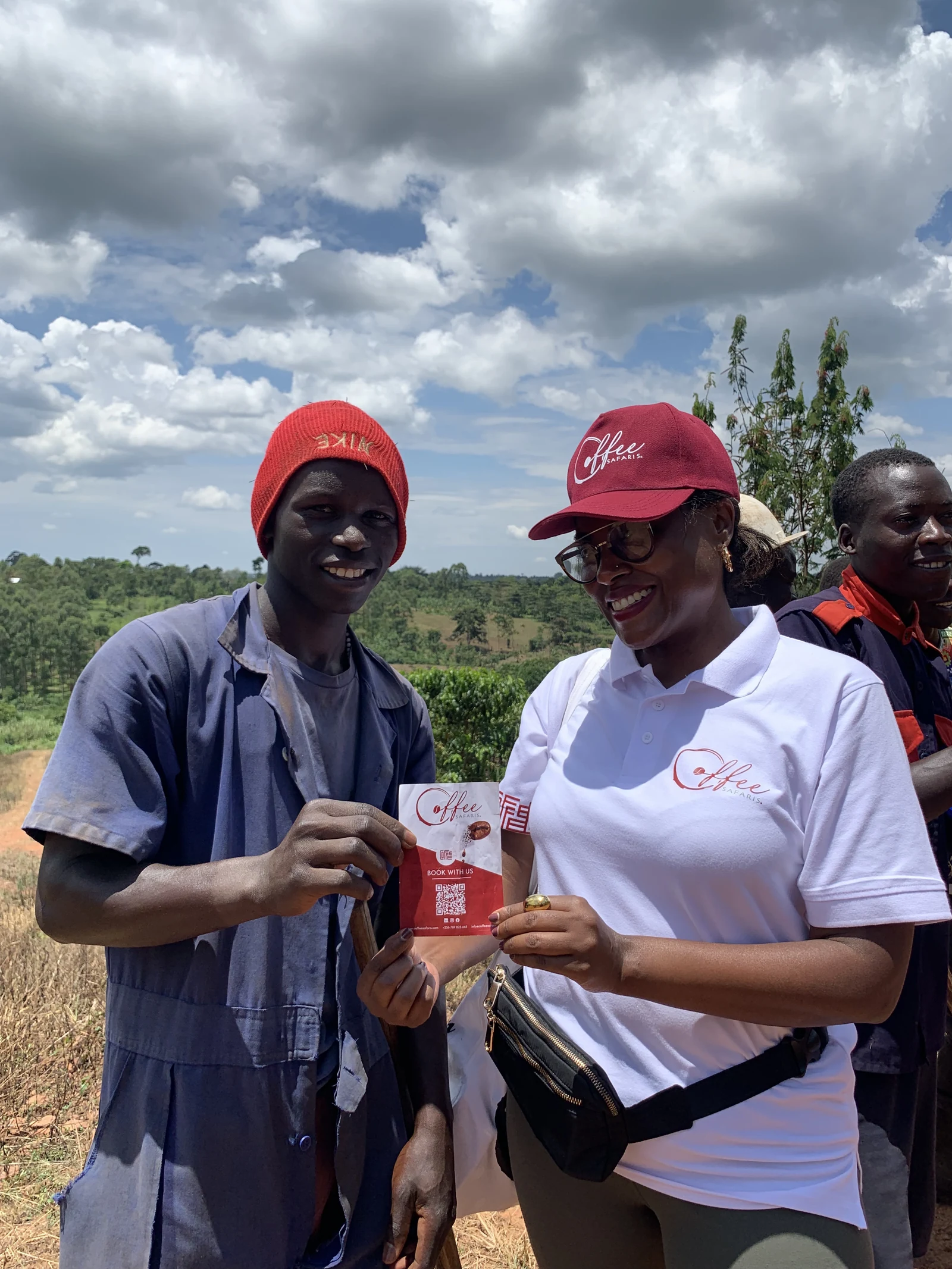 A Coffee Safaris team member handing a booking card to a farm worker in the field